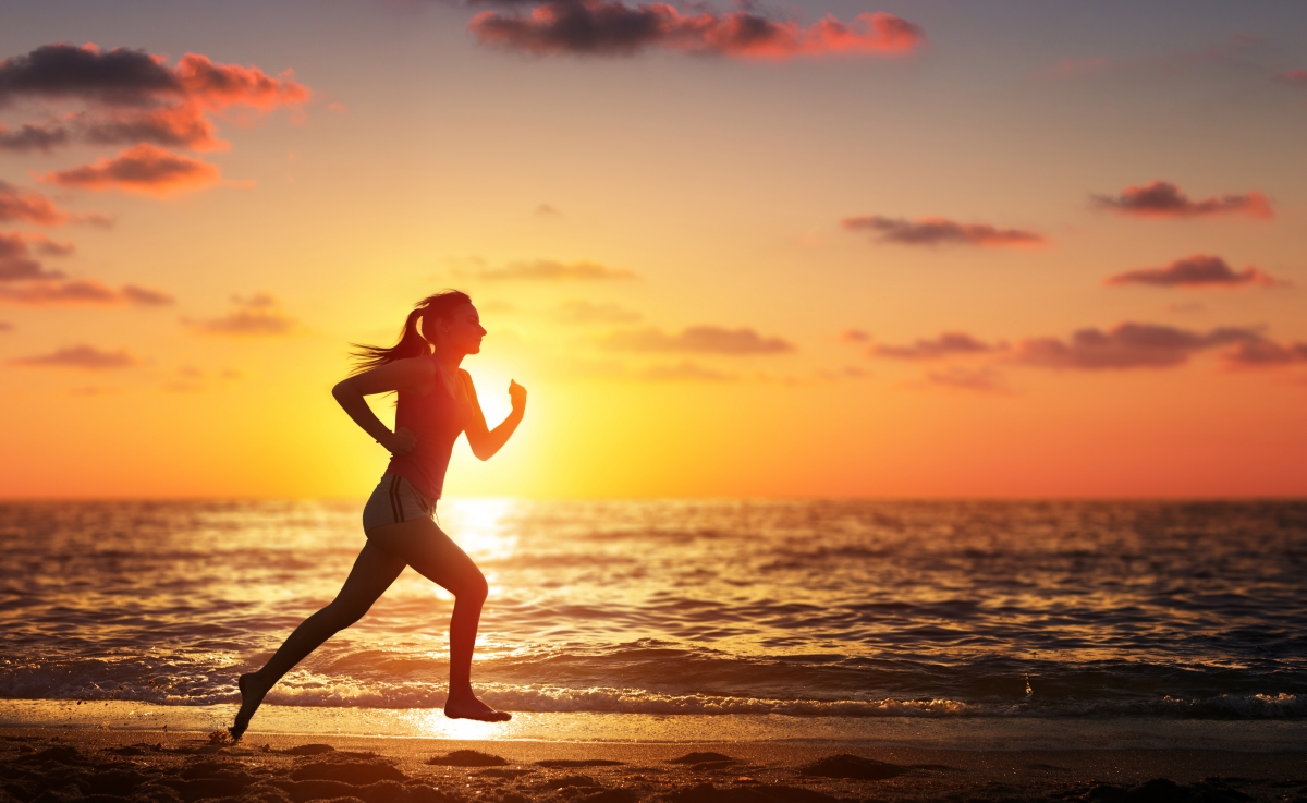 日落时沙滩上奔跑的女人高清图片